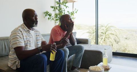 Father and son watching tv and relaxing in modern living room