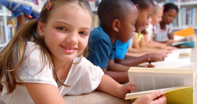 Diverse group of children smiling and reading books together in a library, showcasing multicultural friendship and teamwork. Ideal for use in educational materials, children's learning resources, library promotions, literacy campaigns, and advertisements promoting diversity and inclusive learning.