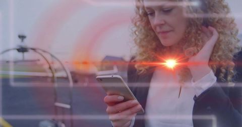 Business traveler checking smartphone on airport tarmac with glowing digital interface