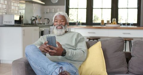Older Man Relaxing on Couch Using Smartphone in Modern Home