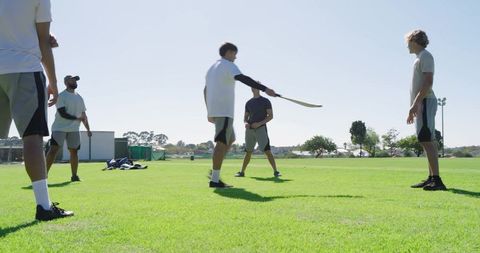 Youth hurling practice demonstrating hurley pass on sunny grass field, teamwork drill