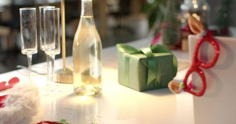 Green Gift Box with Champagne Bottle and Flutes Creating Cozy Holiday Table Ambience