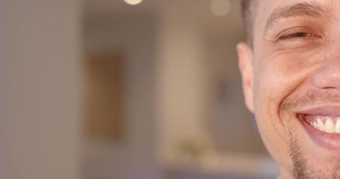 Smiling man presenting warm half-face close-up with cozy interior bokeh and copy space