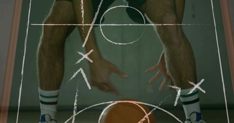 Reaching basketball player dribbling low with striped socks and tactical playbook markings
