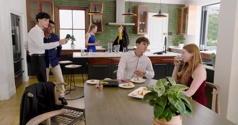 Multiracial friends socializing in modern open-plan kitchen enjoying drinks and chat