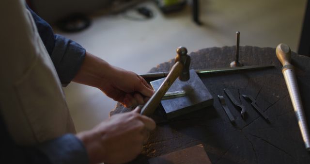Close up of hands of caucasian female jeweller using hammer, making jewelry. independent handmade craft business.