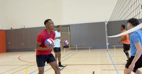 Diverse male volleyball players practicing team drills in indoor gymnasium