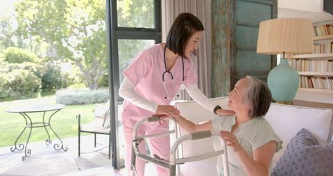 Nurse Assisting Senior Woman with Walker in Bright Living Room