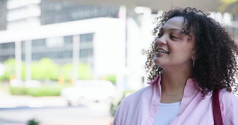 African american woman walking downtown wearing pink shirt and carrying red bag