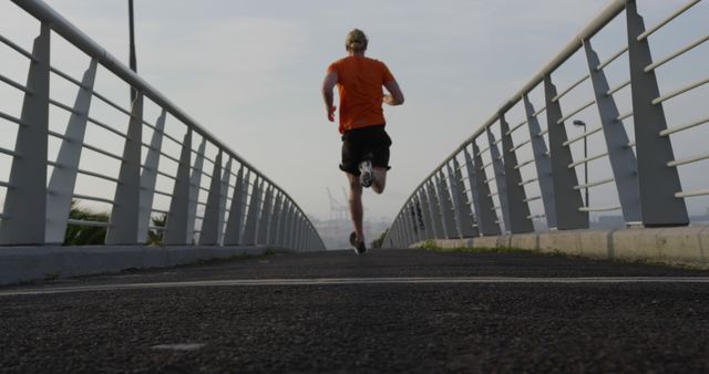 Rear View of Man Running on Urban Bridge during Morning Exercise - Download Free Stock Images Pikwizard.com