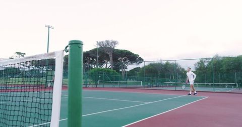 Male tennis player standing at baseline holding racket on outdoor court