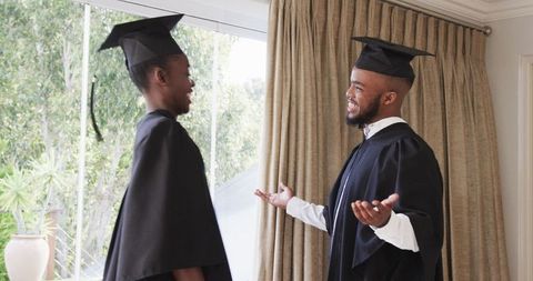 Graduates celebrating milestone in graduation gowns indoors