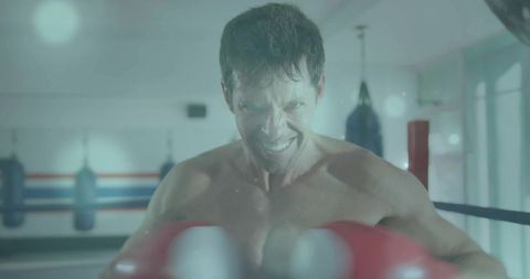 Male boxer throwing powerful red-gloved punch in ring, intense training focus