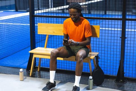 Young male padel player relaxing on bench before match