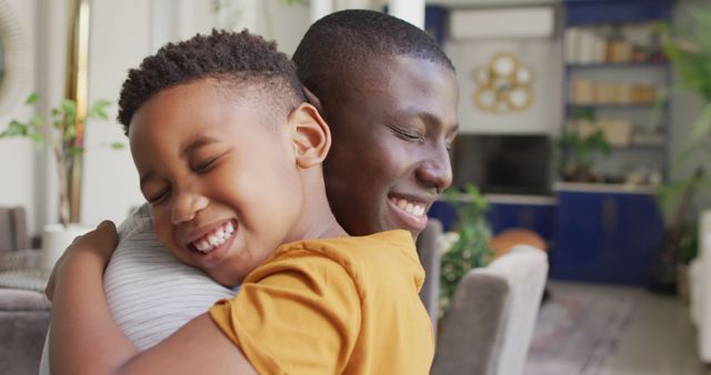 Image of happy african american father and son hugging at home. Family, spending quality time together at home concept.