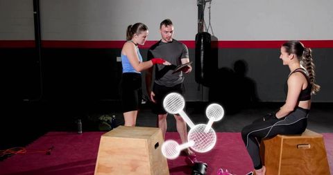 Female trainee pointing while coach reviewing tablet during boxing training