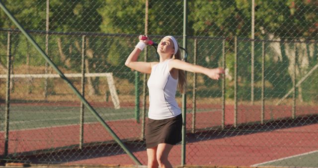 Female tennis player serving on outdoor court during sunny day - Download Free Stock Images Pikwizard.com