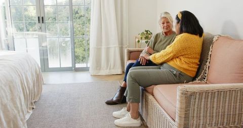 Senior Mother and Daughter Chatting on Cozy Wicker Sofa