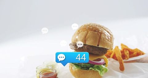 Cheeseburger with social notification bubble showing 44 and sweet potato fries on white countertop