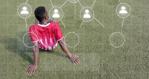 Black soccer player resting on turf with digital network overlay showing team connections