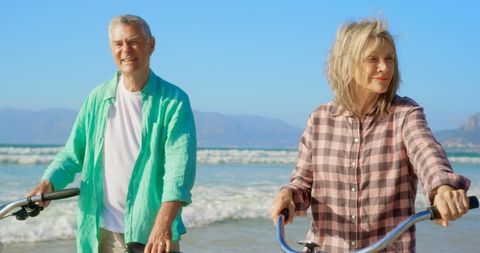 Happy Senior Couple Enjoying Bike Ride on Beach Shoreline