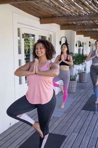 Diverse Women Practicing Yoga in Tree Pose on Deck