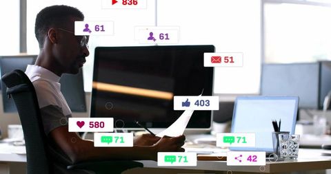 Office worker reading documents while digital notifications crowding computer monitors