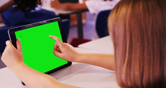 Little girl using tablet with green screen in classroom