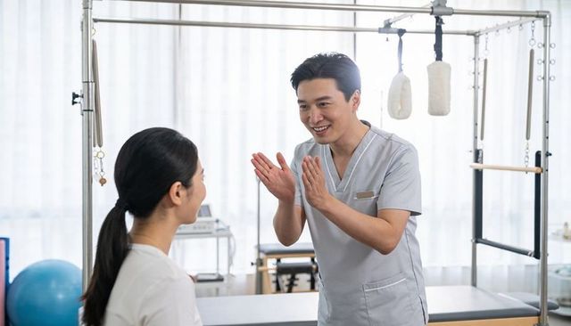 Male therapist guiding patient through rehabilitation exercises in bright clinic