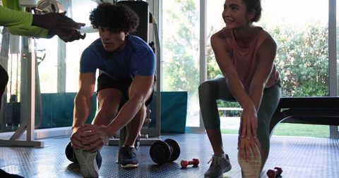 Couple Practicing Stretching Routine in Well-Equipped Gym