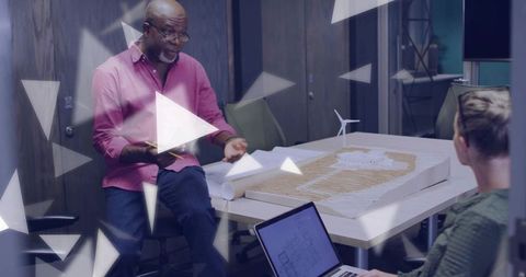 Senior architect mentoring junior designer over scale model and blueprints in office