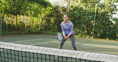 Female Athlete Bracing and Holding Racket in Ready Tennis Stance on Outdoor Hard Court