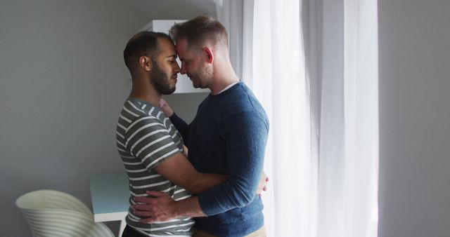 Multi ethnic gay male couple embracing and smiling. enjoying staying at home in self isolation in quarantine lockdown.