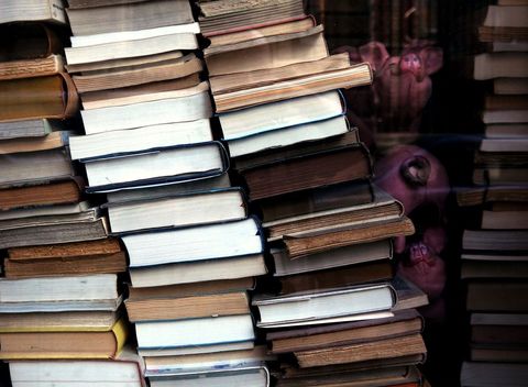 Stack of vintage books with person peeking through window