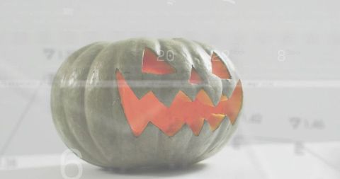 Glowing green jack-o'-lantern sitting on minimalist tabletop with numeric overlay