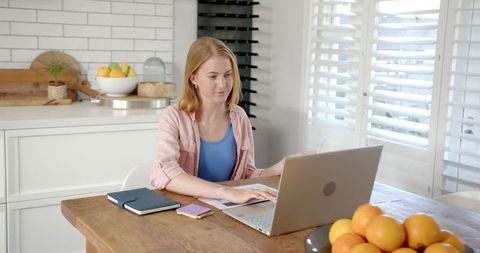 Woman Working on Laptop at Modern Kitchen Table