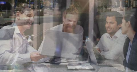 Colleagues Collaborating Through Window Reflection with Laptops and Documents Urban Office