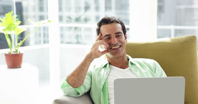 Happy Man Dressed in Light Green Shirt Working on Laptop at Home - Download Free Stock Images Pikwizard.com