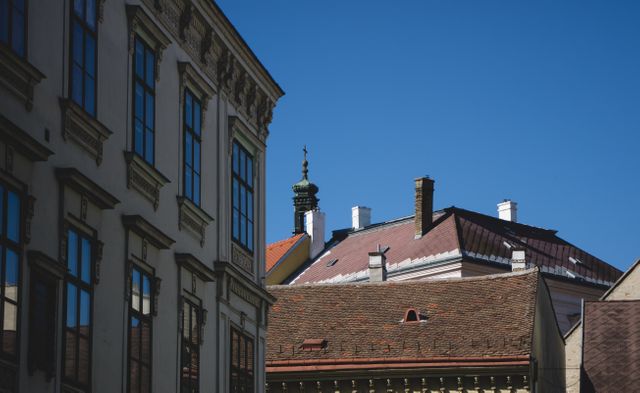 Photograph capturing the rooftops of European buildings under a clear blue sky. Ideal for projects focused on architectural heritage, urban design, travel, and European culture. Great for websites, blogs, and print material depicting historic cityscapes.