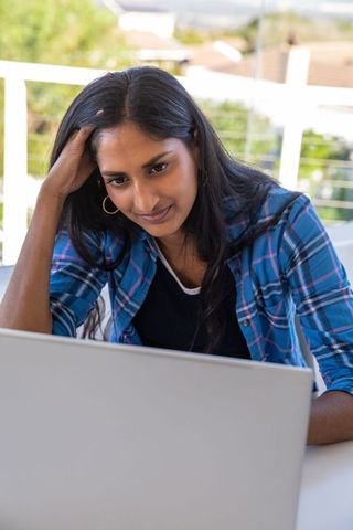 Young Woman Typing on Laptop Outdoors with Relaxed Expression