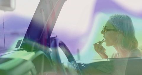 Glamorous woman applying lipstick in car with sophisticated style