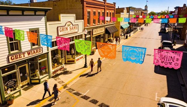 Colorful papel picado banners across historic small town main street celebrating summer festival