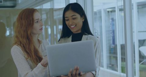 Colleagues Reviewing Work on Laptop in Modern Office Setting