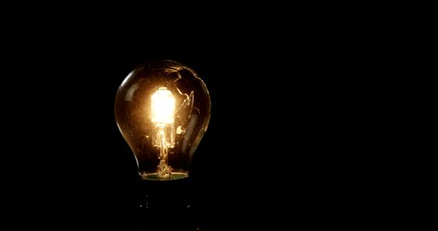 A glowing light bulb stands out against a dark background, with copy space. Its illumination symbolizes ideas, innovation, and creativity.