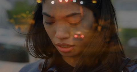 Reflective Woman Observing Urban Light Streaks Through Glass