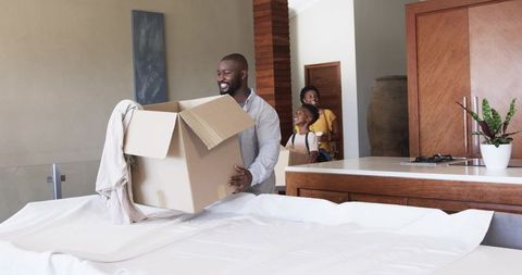 Smiling African American family moving and unpacking boxes in modern open-plan kitchen