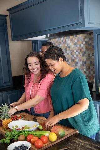 Friends prepping fruit salad in modern kitchen
