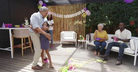 Grandfather Twirling Granddaughter During Backyard Birthday Celebration With Family
