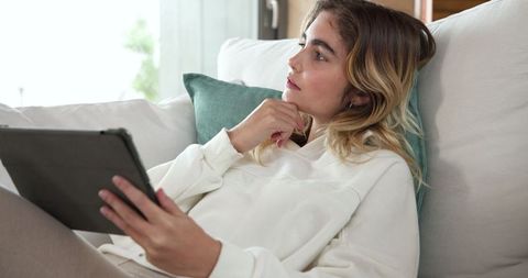 Young woman relaxing on sofa with tablet at home
