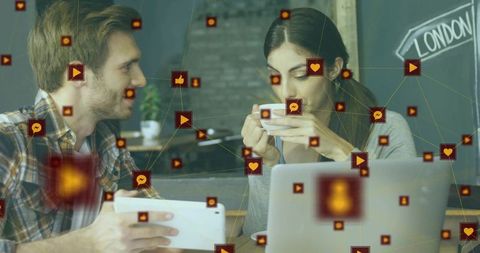 Young professionals networking over coffee using tablet and laptop with social media icons overlay